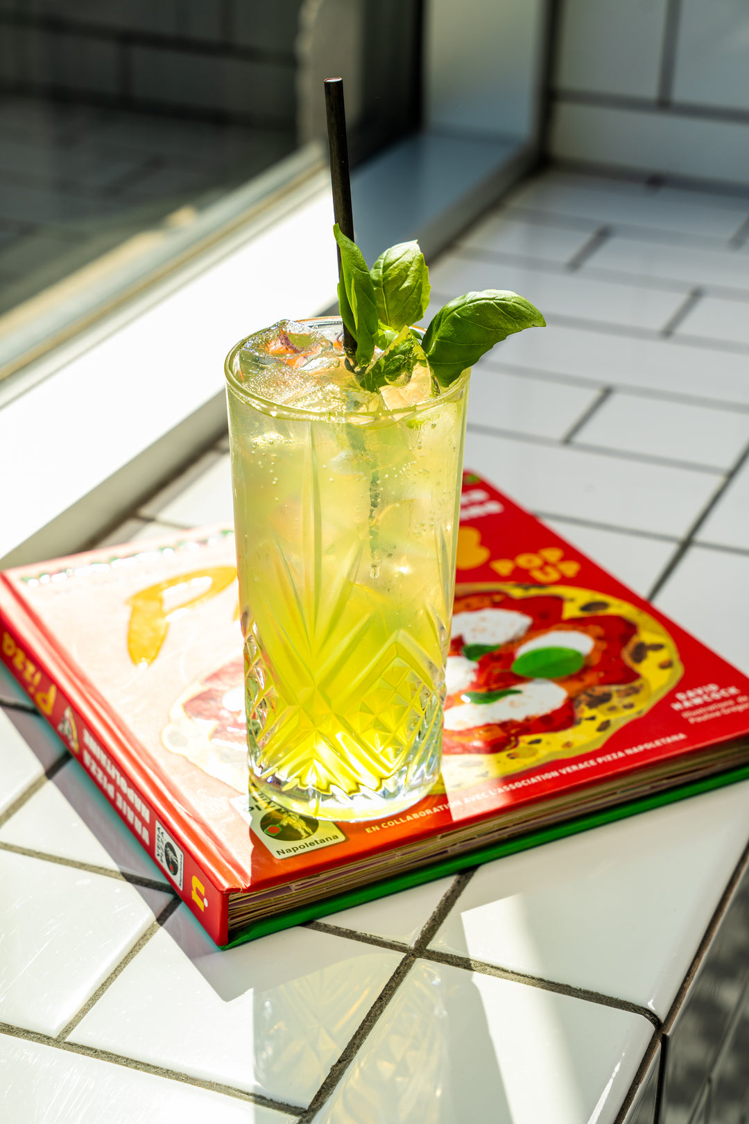 Un gin tonic au basilic sur un livre.