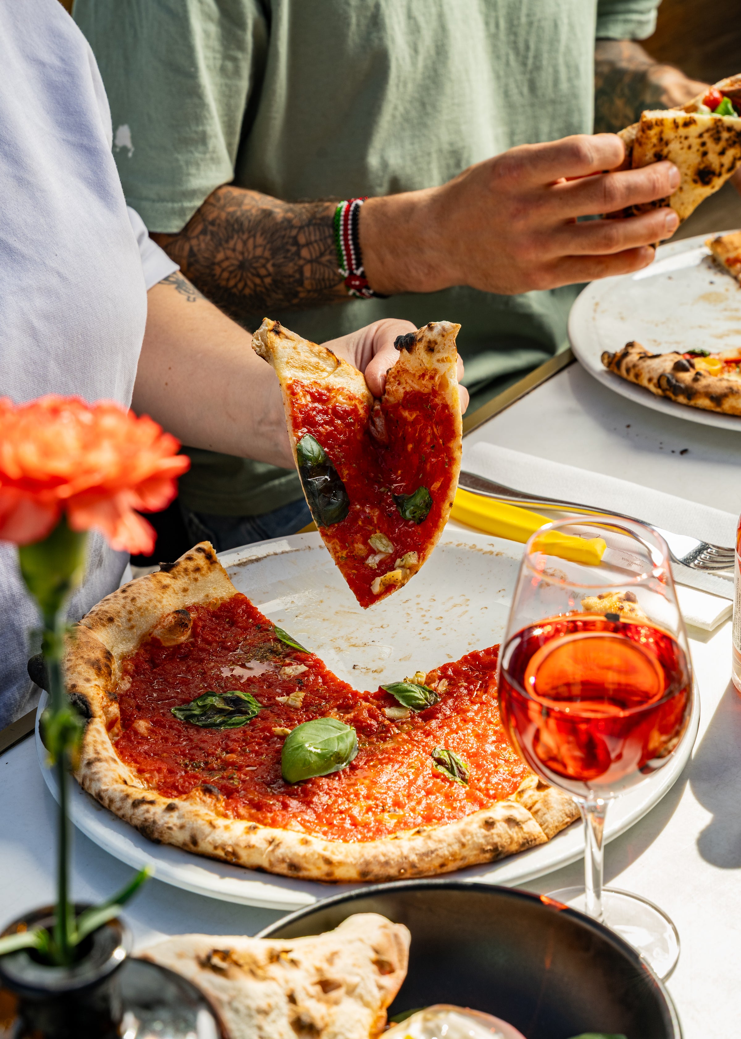 Une pizza marinara avec du basilic et un verre de vin.