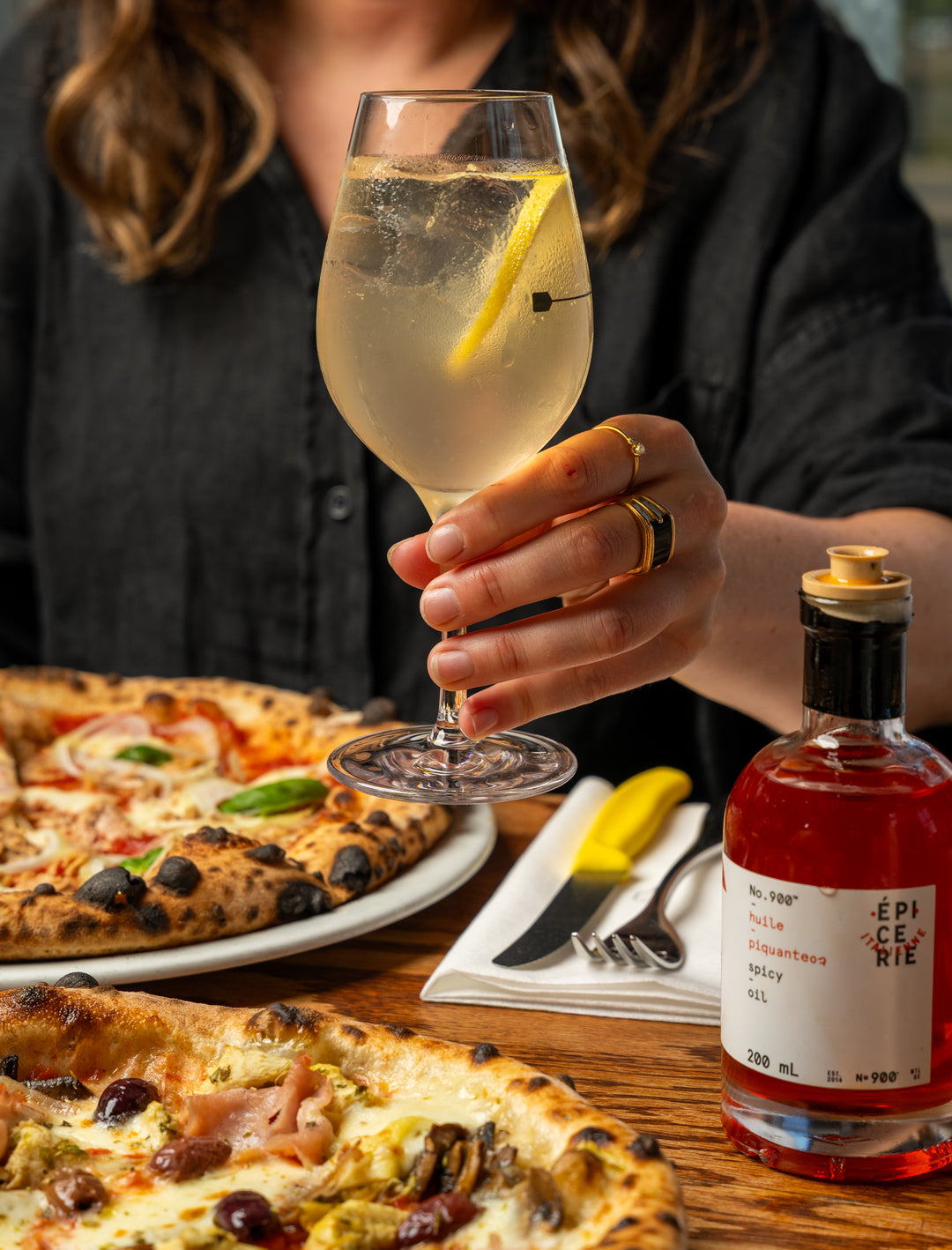 Une sangria blanche dans une main avec une pizza et de l'huile épicée.